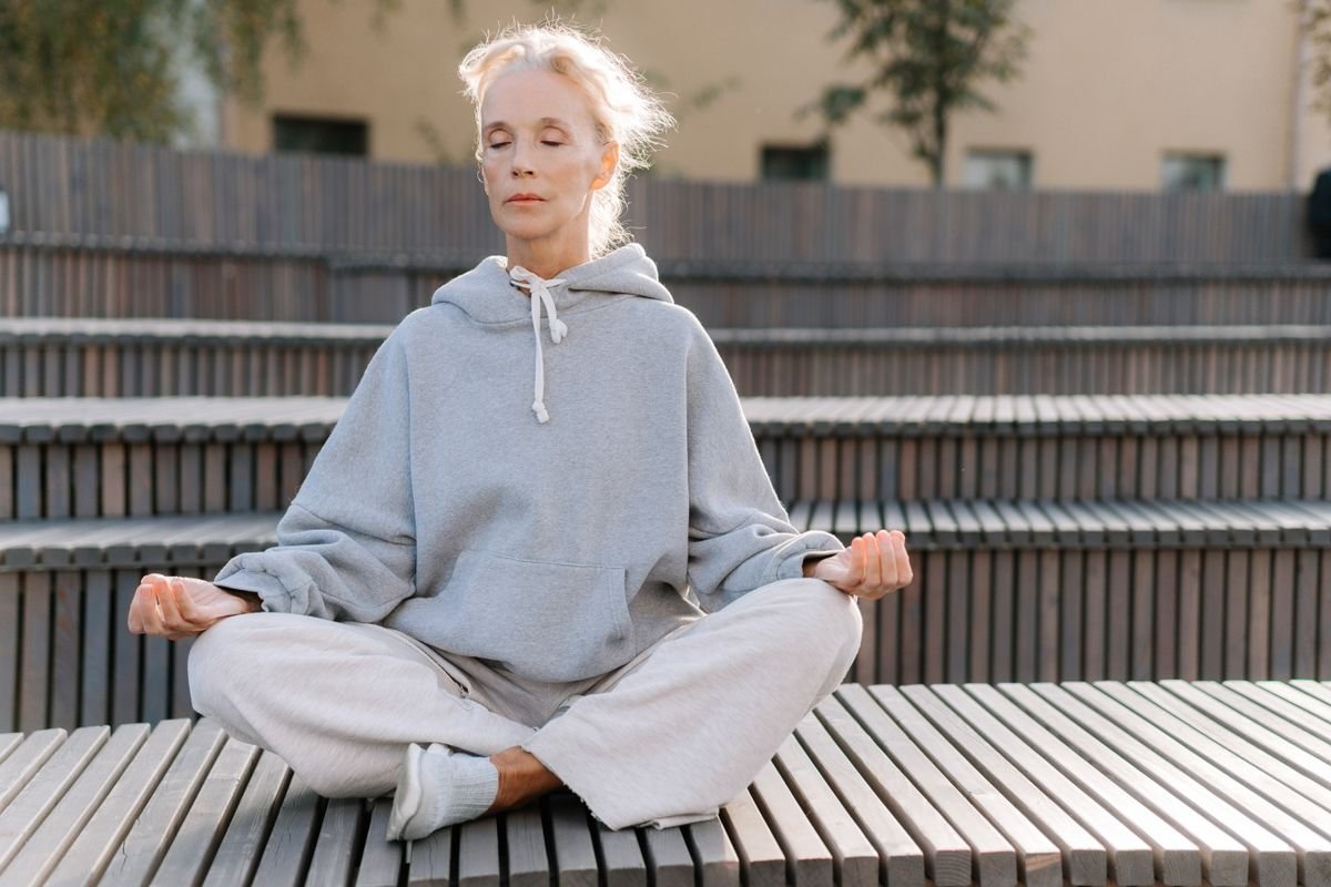 Pessoa meditando ao ar livre com expressão de abertura e receptividade, olhos suavemente fechados, postura relaxada
